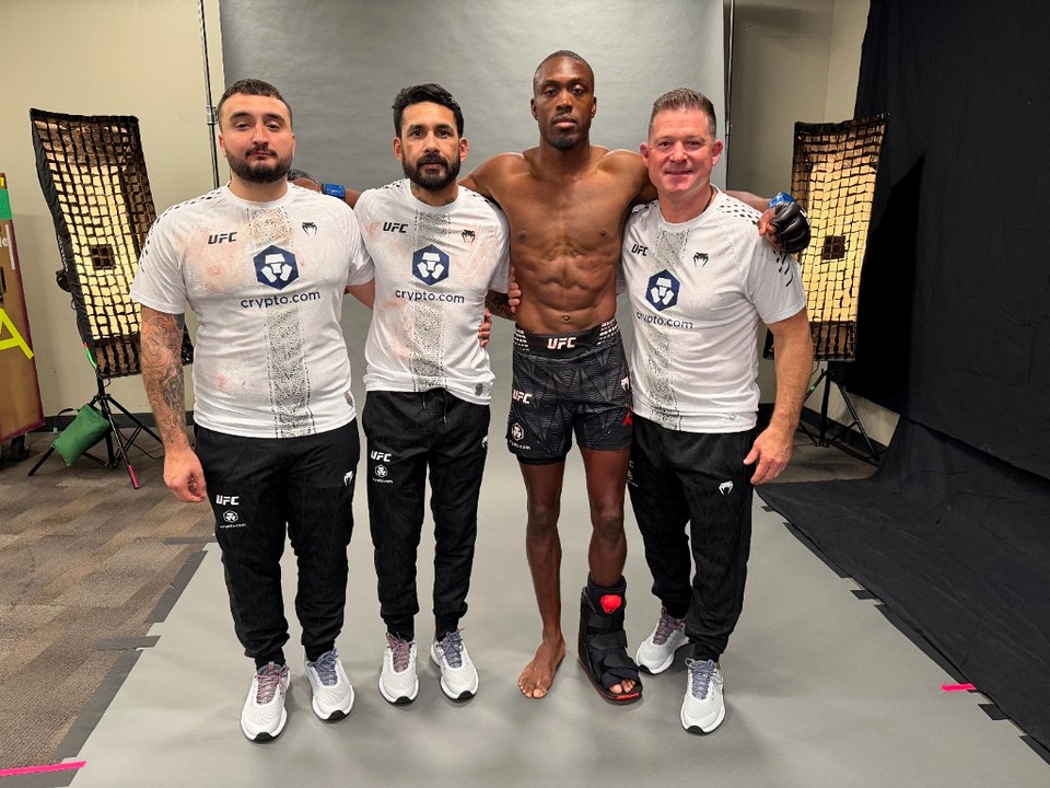 Post-fight victory photo with corner team at UFC 323